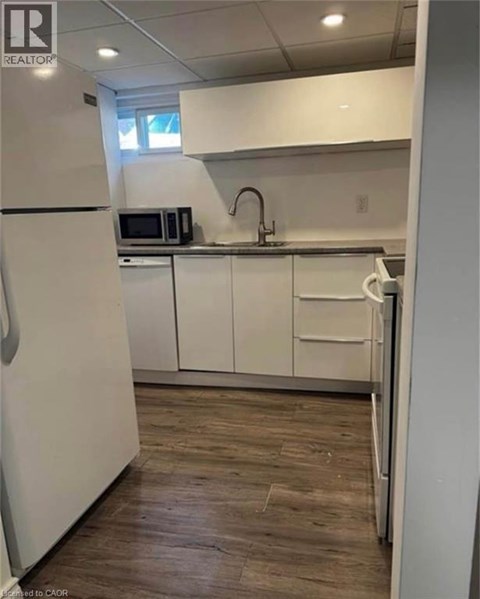 A kitchen with white cabinets and a wooden floor.