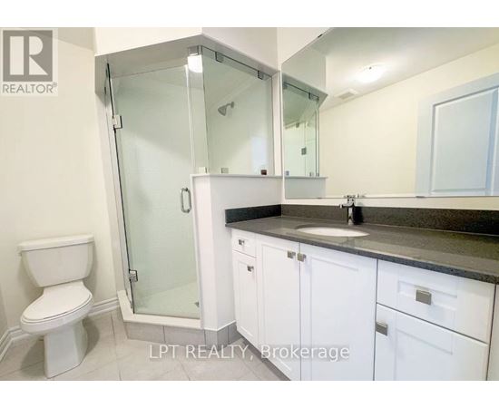 A white toilet sits next to a walk-in shower in a bathroom.