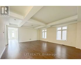 A spacious room with wooden flooring and white walls, with a doorway leading to another room.