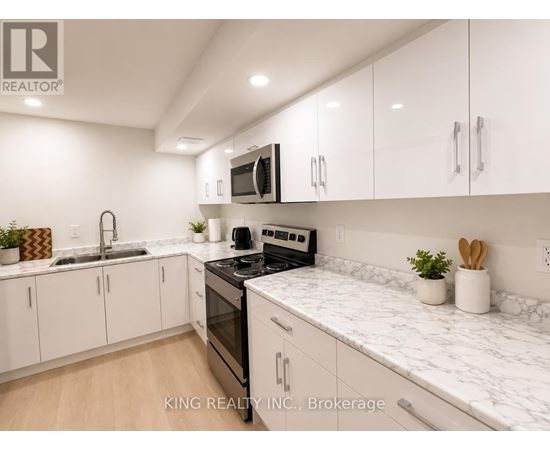 A modern kitchen with white cabinets and marble countertops.