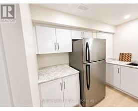 A kitchen with a stainless steel refrigerator and white cabinets.