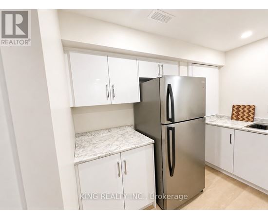 A kitchen with a stainless steel refrigerator and white cabinets.