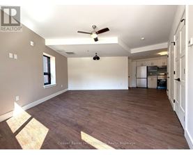 A spacious room with wooden flooring and a ceiling fan.