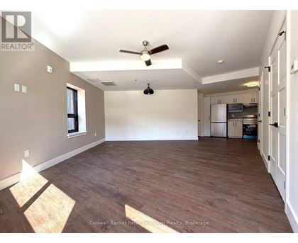 A spacious room with wooden flooring and a ceiling fan.