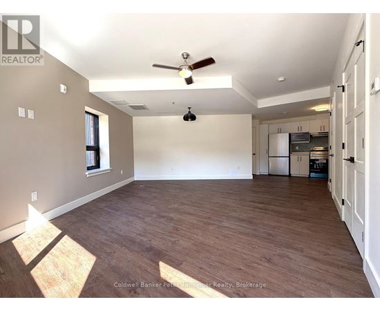 A spacious room with wooden flooring and a ceiling fan.