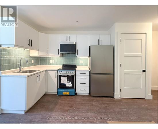 A kitchen with white cabinets and a stainless steel refrigerator.