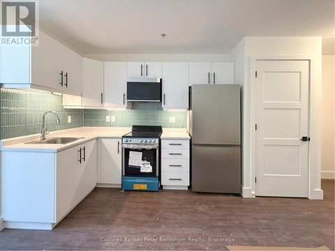 A kitchen with white cabinets and a stainless steel refrigerator.
