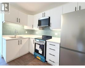 A kitchen with white cabinets and a black microwave.