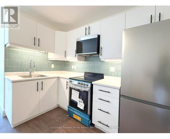 A kitchen with white cabinets and a black microwave.