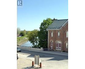 A building with a red brick facade and white trim is situated next to a body of water.