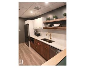 A kitchen with a sink, refrigerator, and wooden cabinets.
