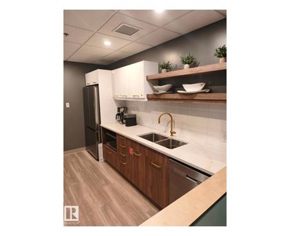 A kitchen with a sink, refrigerator, and wooden cabinets.