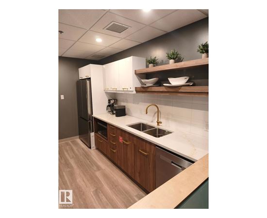 A kitchen with a sink, refrigerator, and wooden cabinets.