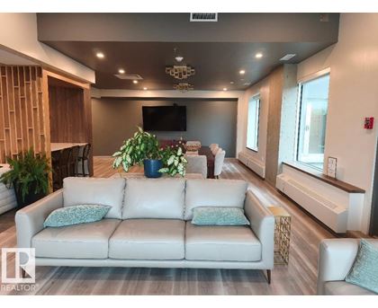 A living room with a white couch and a flat screen TV mounted on the wall.