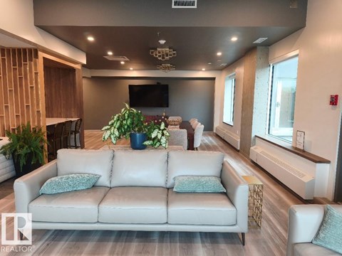 A living room with a white couch and a flat screen TV mounted on the wall.