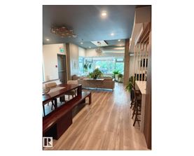 A long wooden table is in the middle of a room with a glass window.