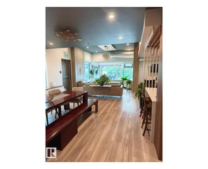 A long wooden table is in the middle of a room with a glass window.