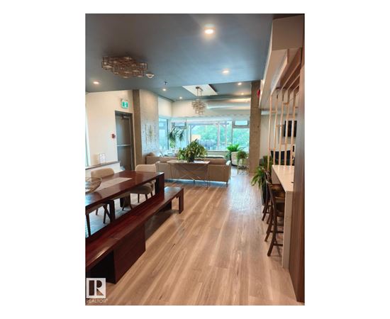 A long wooden table is in the middle of a room with a glass window.