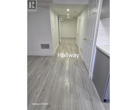 A hallway with wood flooring and white walls.