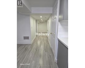 A hallway with wood flooring and white walls.