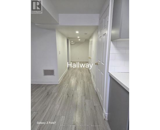 A hallway with wood flooring and white walls.