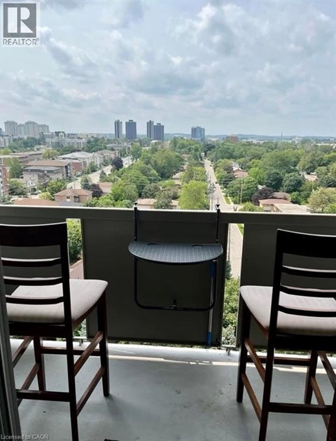 Two chairs are placed on a balcony overlooking a cityscape.