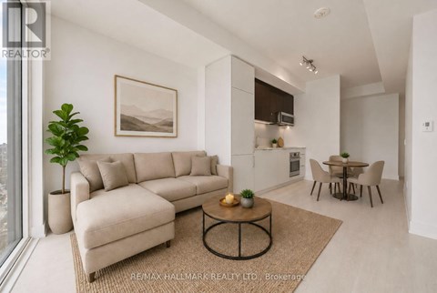 A living room with a beige sofa, a coffee table, and a dining table with chairs.