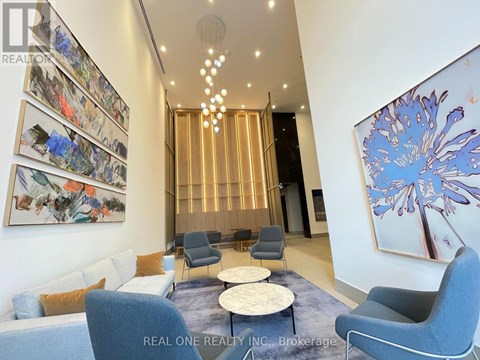 A living room with a blue sofa, grey armchairs, and a large abstract painting on the wall.