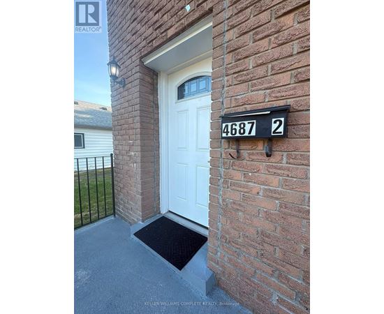 A white door is on the front of a brick building with a black mailbox that has the number 4687 on it.