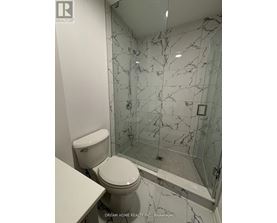 A white toilet in a bathroom with a marble wall.