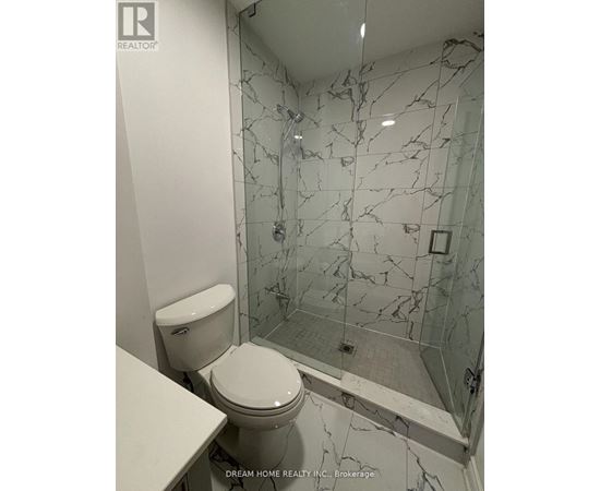 A white toilet in a bathroom with a marble wall.