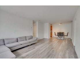 A grey sofa sits in a spacious room with wooden flooring.
