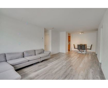 A grey sofa sits in a spacious room with wooden flooring.