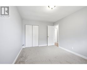 A white bedroom with a carpet floor and a white door.