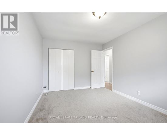 A white bedroom with a carpet floor and a white door.