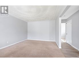 A white room with a carpet floor and a door on the right side.