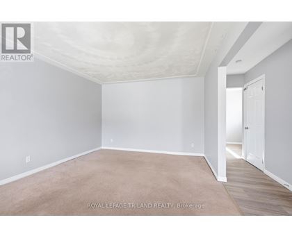 A white room with a carpet floor and a door on the right side.