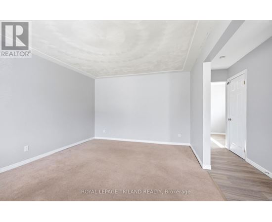 A white room with a carpet floor and a door on the right side.