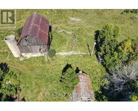 An old barn with a rusted roof sits in a grassy field.
