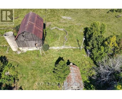 An old barn with a rusted roof sits in a grassy field.