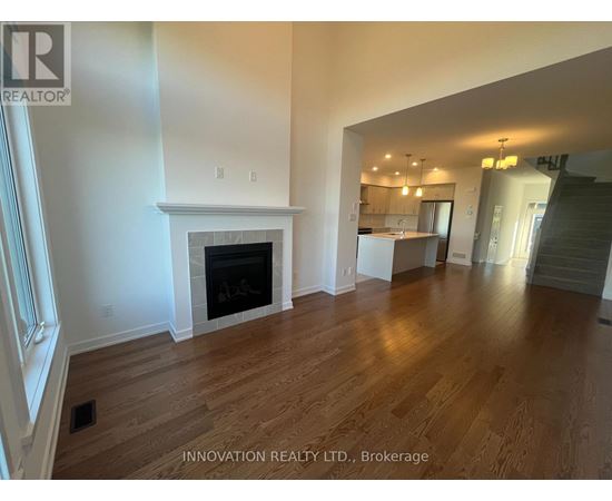 A spacious room with a fireplace and wooden flooring.