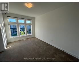 A room with a carpeted floor and a window showing a view of a building and some plants.