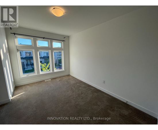 A room with a carpeted floor and a window showing a view of a building and some plants.