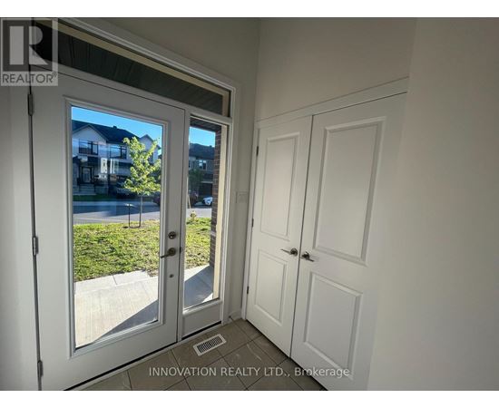 A white door with a glass window is open, showing a residential area outside.