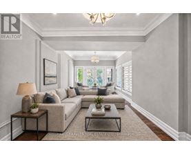 A well-lit, spacious living room with a large sectional sofa, a coffee table, and a chandelier.