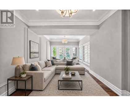 A well-lit, spacious living room with a large sectional sofa, a coffee table, and a chandelier.