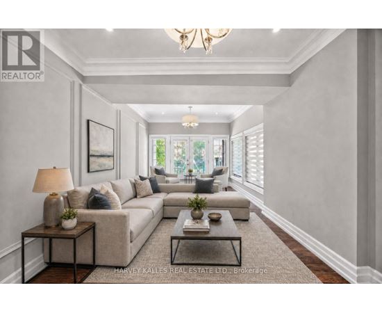 A well-lit, spacious living room with a large sectional sofa, a coffee table, and a chandelier.