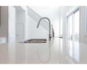 A kitchen with a white countertop and a stainless steel sink.