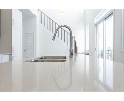 A kitchen with a white countertop and a stainless steel sink.