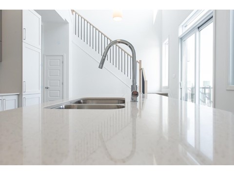 A kitchen with a white countertop and a stainless steel sink.